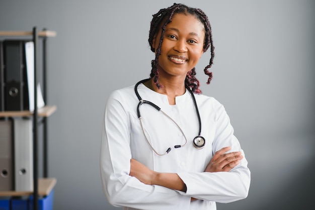 Retrato de médica sorridente usando jaleco branco e estetoscópio no consultório do hospital