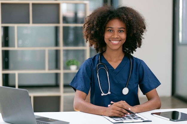 Retrato de médica sorridente usando jaleco branco e estetoscópio no consultório do hospital