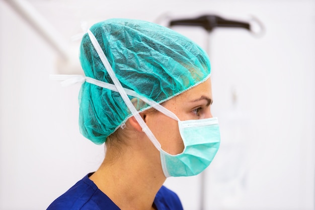 Retrato de médico com máscara protetora e chapéu na sala de cirurgia