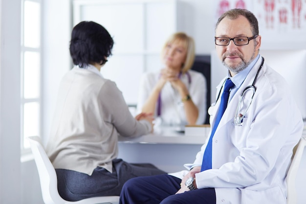 Retrato de médico sênior no escritório sentado na mesa