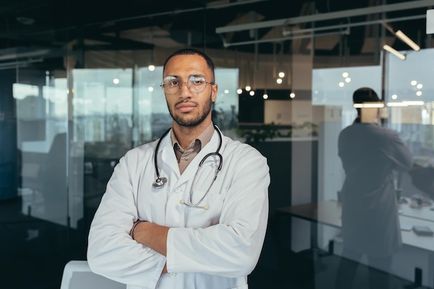 Retrato de médico sério e bem-sucedido em vestido médico olhando pensativamente para a câmera trabalhando