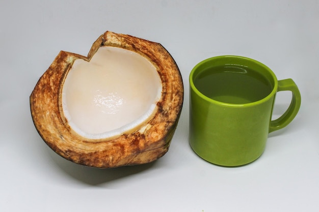 Foto retrato de meio coco partido com um copo de água de coco em um copo verde