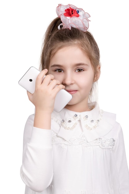 Retrato de meio comprimento de uma menina em um vestido branco com telefone inteligente branco na mão isolado no fundo branco