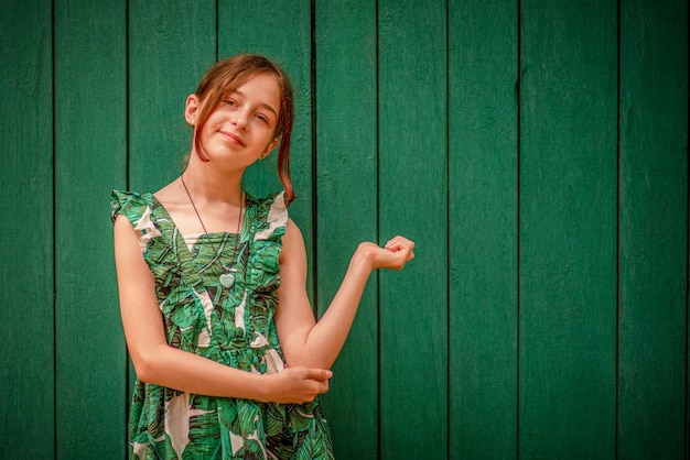 Retrato de menina adolescente em um vestido em um fundo verde. Menina de 10 ou 11 anos em um dia de verão.