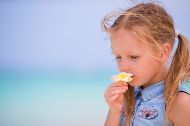 Retrato de menina adorável com flores nas férias de verão na praia