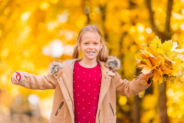 Retrato de menina adorável com folhas amarelas buquê no outono