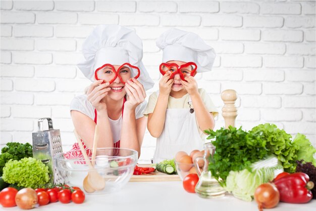 Retrato de menina adorável e sua mãe cozinhando juntos