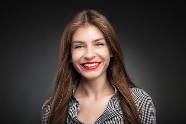 Retrato de menina adorável sorri com batom vermelho nos lábios. Retrato de estúdio em fundo preto vinheta.