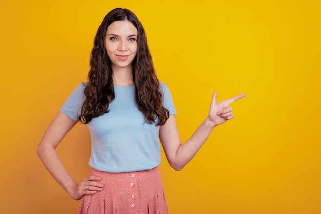 Retrato de menina alegre e animada apontar o dedo indicador espaço vazio anúncios promoção recomendar sugerir isolado sobre fundo de cor brilhante