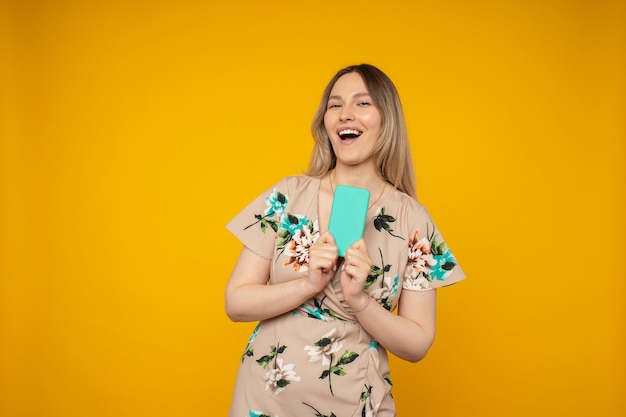 Retrato de menina alegre positiva usar telefone inteligente compartilhar notícias de mídia social vestir estilo elegante vestido moderno isolado sobre fundo de cor amarela