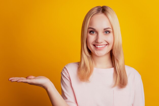 Retrato de menina alegre segurando o espaço da cópia em fundo amarelo