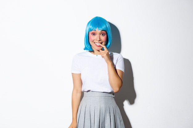 Retrato de menina asiática boba com peruca azul, sorrindo e parecendo curiosa