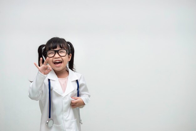 Retrato de menina asiática bonitinha em uniforme médico em fundo branco