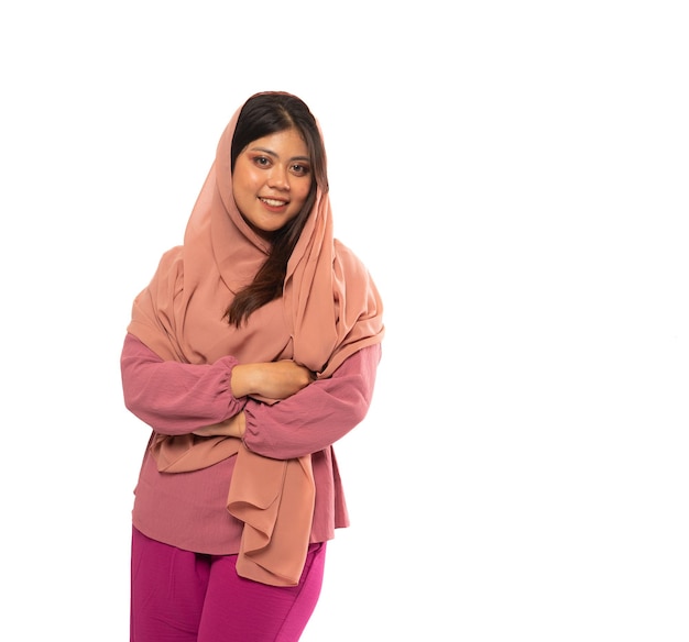 Retrato de menina asiática em hijab em pé com as mãos cruzadas em um fundo isolado