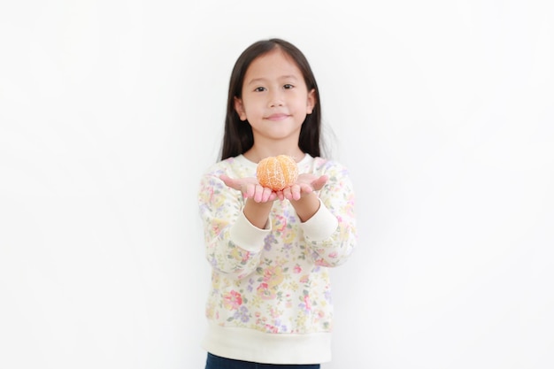 Retrato de menina asiática segurando fruta laranja descascada em fundo branco Foco em laranja nas mãos