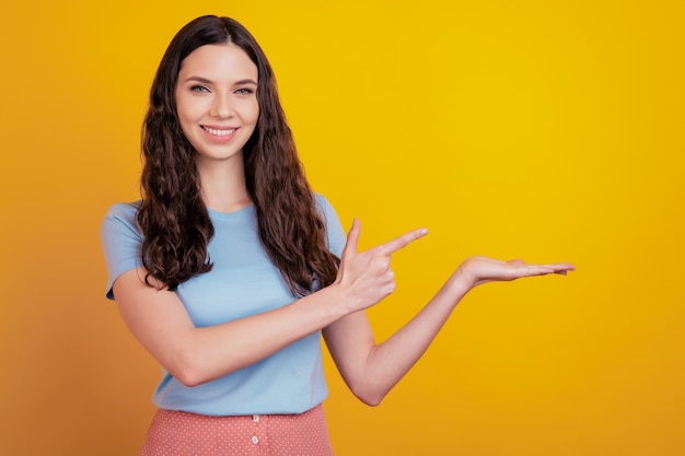 Retrato de menina atraente apontar o dedo indicador espaço vazio produto oferecer anúncios recomendar isolado sobre fundo de cor brilhante