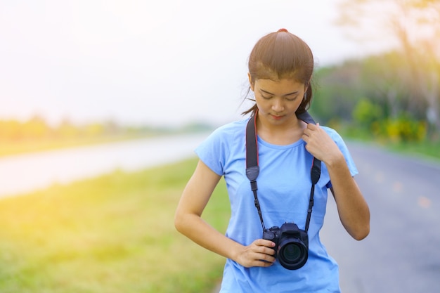 Retrato, de, menina bonita, em, azul, t-shirt, e, calças brim, sorrindo, com, um, câmera, ligado, mãos