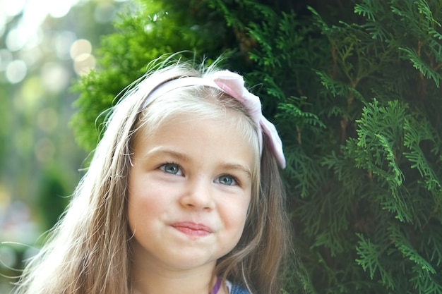 Retrato de menina bonita em pé ao ar livre no parque de verão.