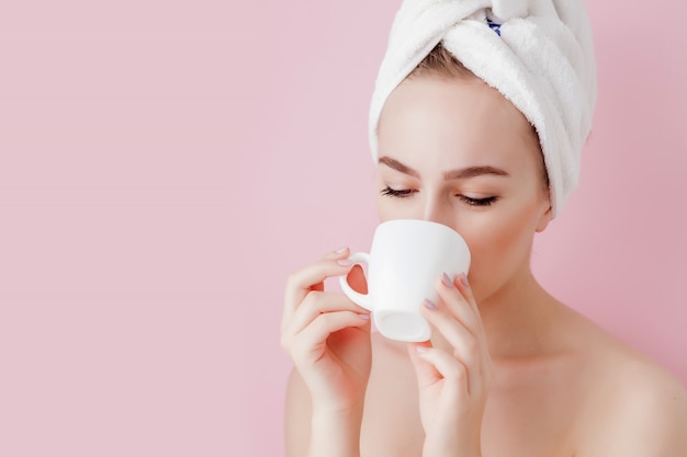 Retrato de menina bonita em roupão com uma xícara de chá, mulher loira de conceito de relaxamento vestindo roupão e toalha na cabeça após o banho. Mulher de spa em roupão e turbante