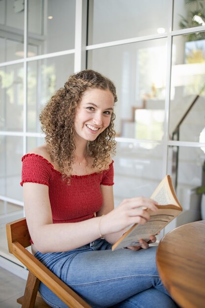 Retrato de menina bonita. mulher sorridente lendo um livro em casa Livro de leitura do conceito de estudo