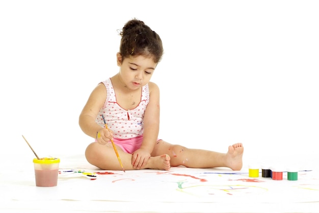 Foto retrato de menina bonita pintando imagens em um fundo branco