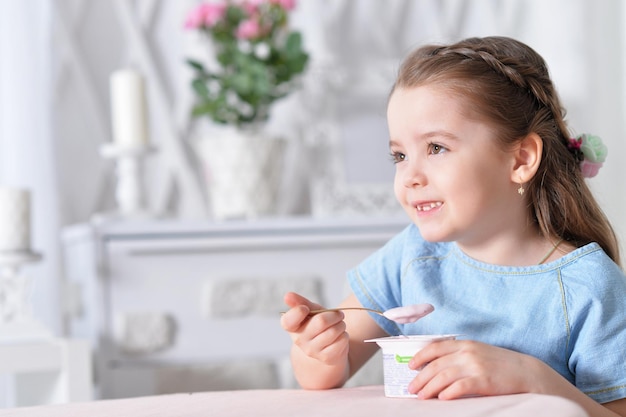 Retrato de menina bonitinha comendo iogurte delicioso