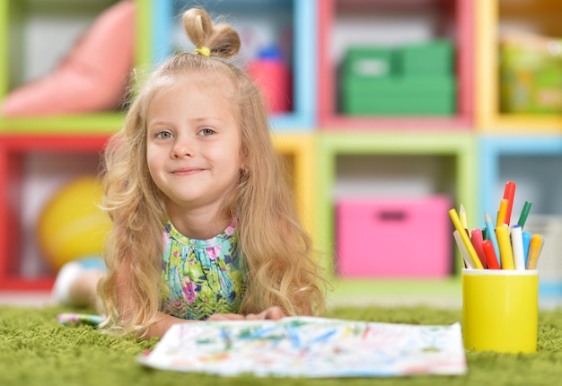 Retrato de menina bonitinha desenhando em casa no chão