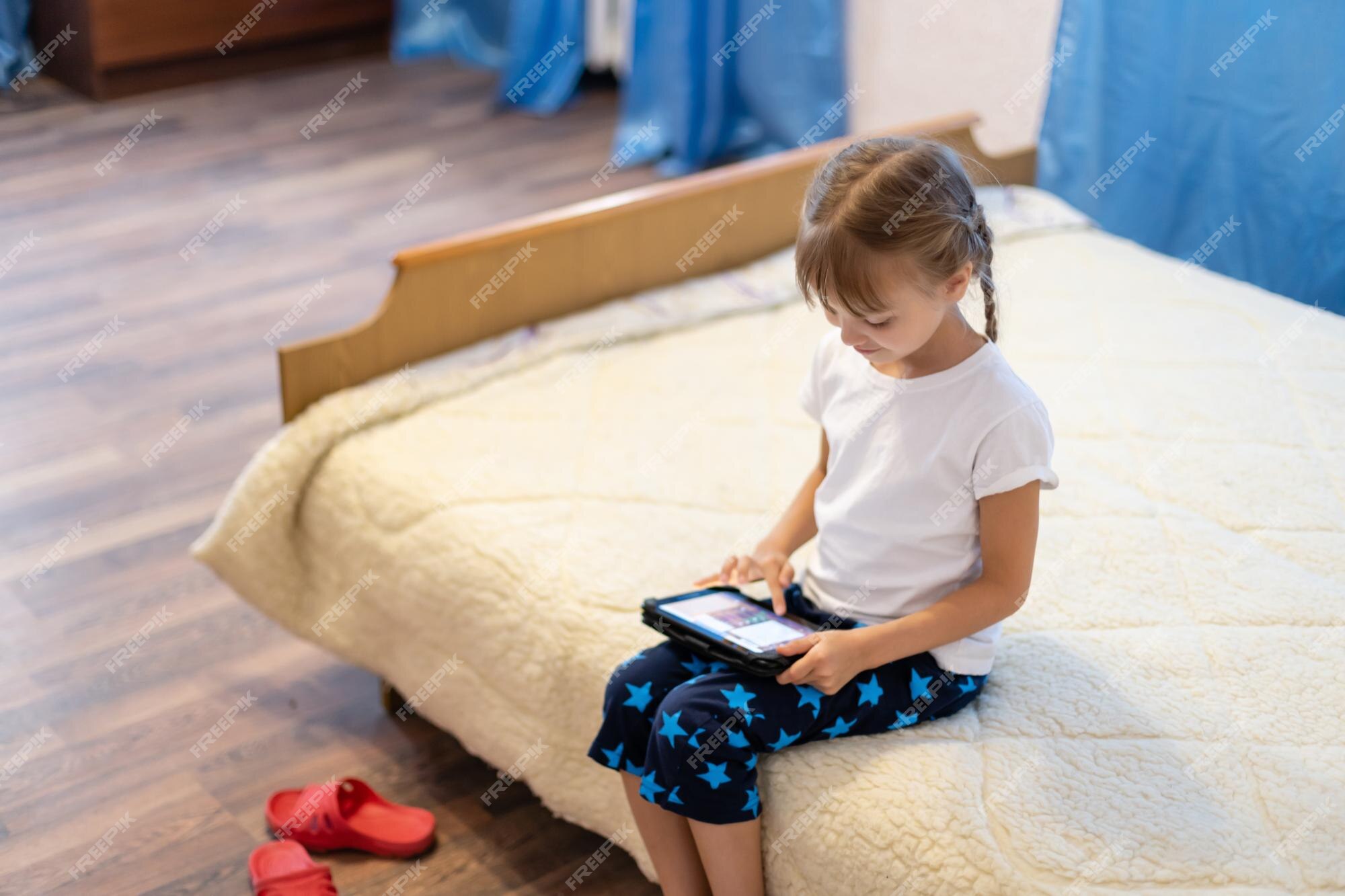 menina bonitinha sentada no chão usando tablet digital tocando a