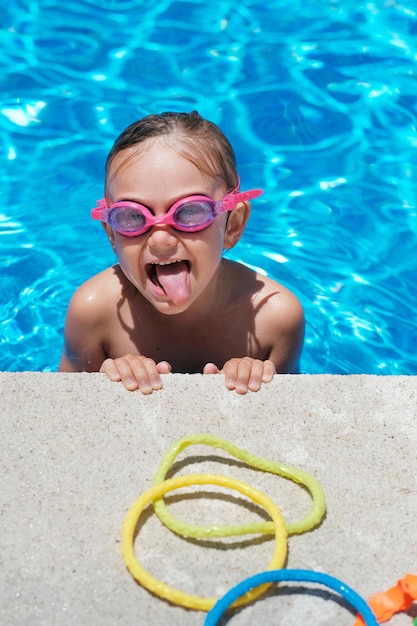 Retrato de menina bonitinha na piscina óculos de sol de verão