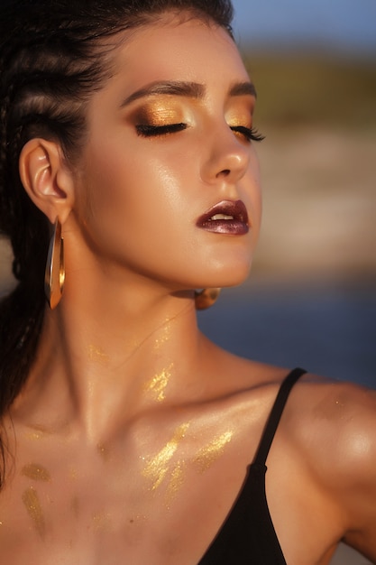 Foto retrato de menina bronzeada à beira-mar. moda verão maquiagem e penteado