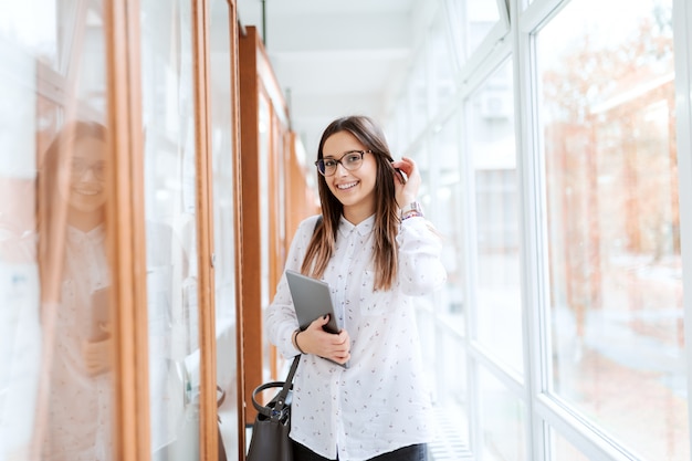 Retrato de menina colagem ao lado de noticeboard com tablet no braço e bolsa no ombro