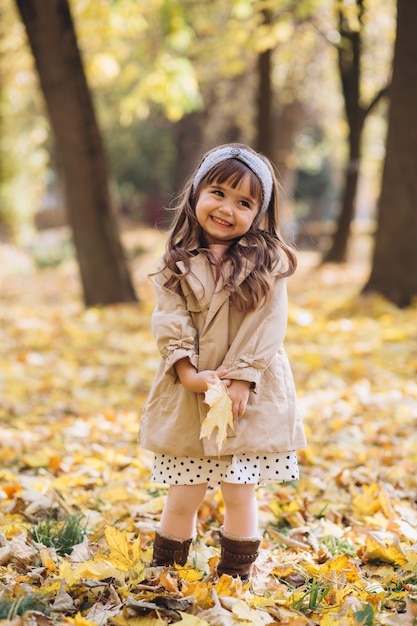 retrato de menina com um casaco bege caminhando no parque de outono