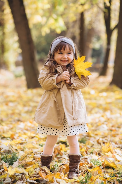 retrato de menina com um casaco bege caminhando no parque de outono