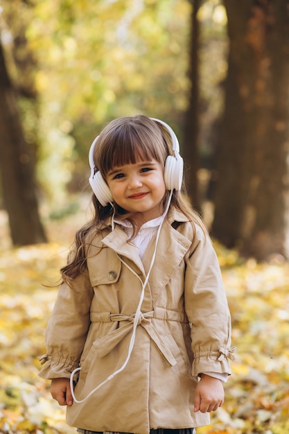 retrato de menina com um casaco bege caminhando no parque de outono