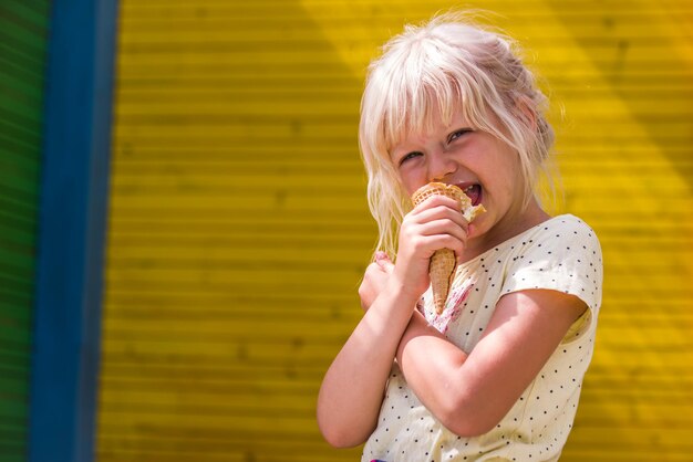 Foto retrato de menina comendo cone de sorvete enquanto está de pé ao ar livre