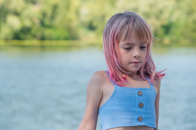 Foto retrato de menina criança fofa. retrato ao ar livre da menina bonitinha em dia de verão. menina com cabelo rosa