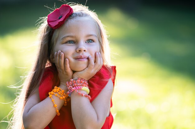 Retrato de menina criança muito elegante com vestido vermelho, aproveitando o dia quente e ensolarado de verão