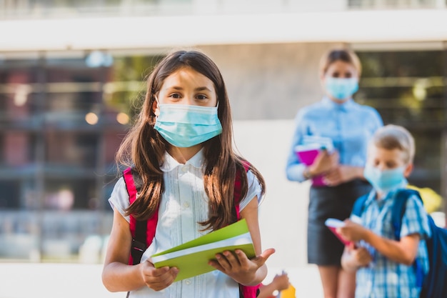 Retrato de menina da escola primária com máscara médica protetora olhando para a câmera As crianças estão felizes por voltar à escola novamente Novas regras de segurança por causa da pandemia