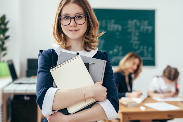 Retrato de menina da escola sorridente com livros em sala de aula