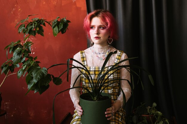 Retrato de menina de cabelo colorido segurando o pote de planta em casa