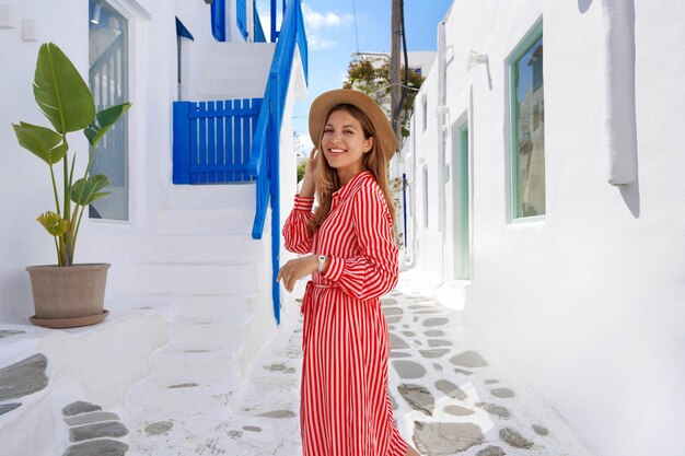 Retrato de menina de vestido listrado caminha pelas ruas estreitas de mykonos grécia europa