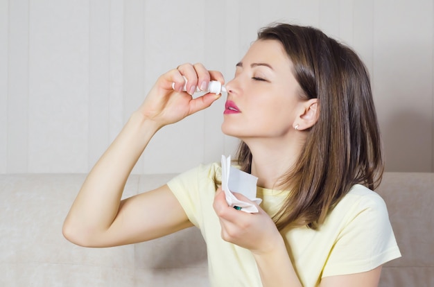 Retrato de menina doente com coriza, rinite, alergias, resfriados. mulher detém spray médico na mão. foco suave