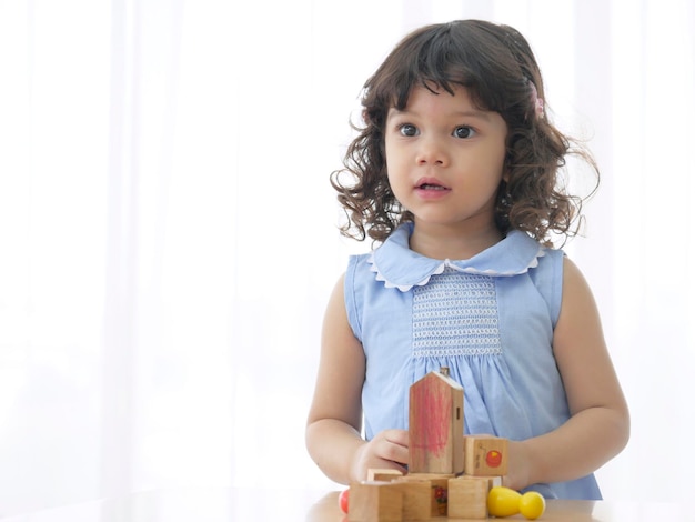 Foto retrato de menina em idade pré-escolar joga blocos de construção na mesa
