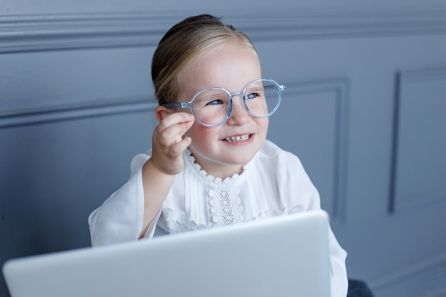 Retrato de menina em óculos atrás de laptop