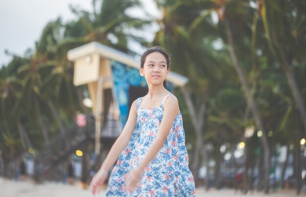 Retrato de menina em pé desfrutar na praia, criança relaxando no céu de noite de verão ao ar livre