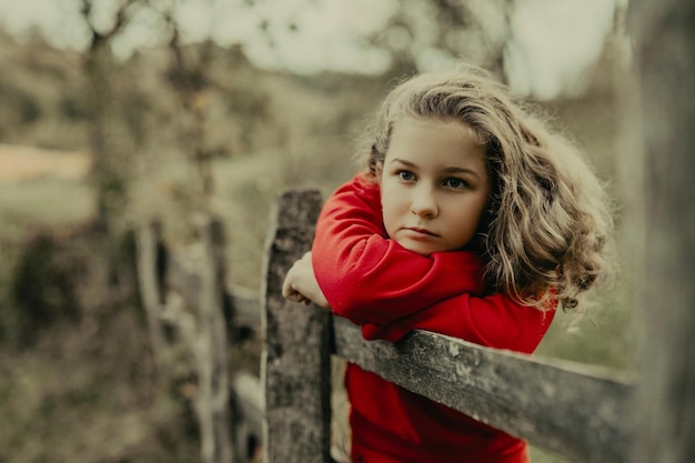 Retrato de menina encostada na cerca de madeira