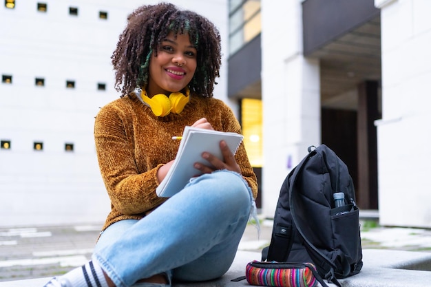 Retrato de menina étnica negra sentada na faculdade fazendo trabalho de classe