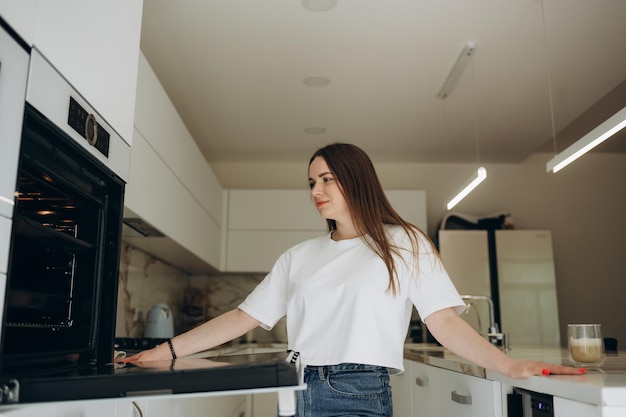 Retrato de menina feliz colocando assadeira no forno de cozinha