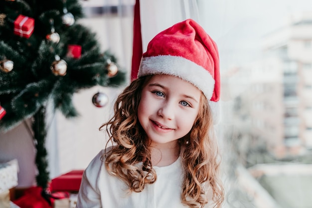Retrato de menina feliz com chapéu na árvore de Natal