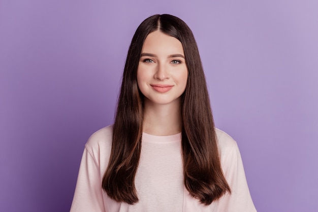 Retrato de menina feliz e positiva posando em fundo violeta